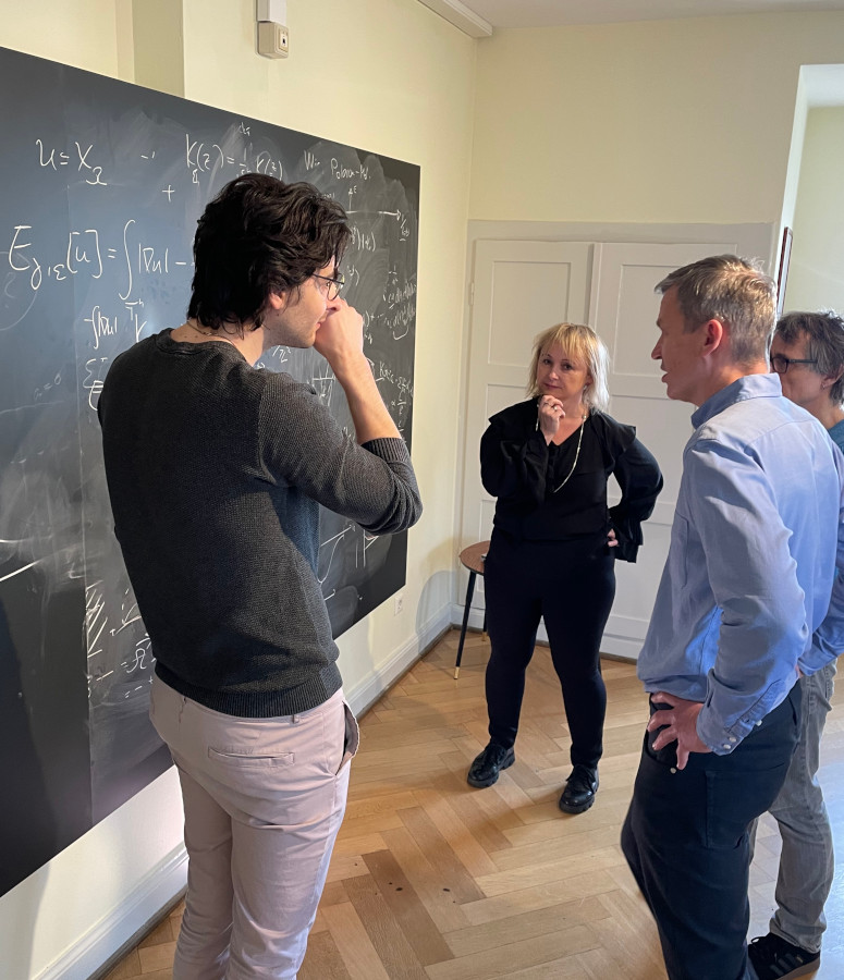 Photo of people discussing in front of a blackboard